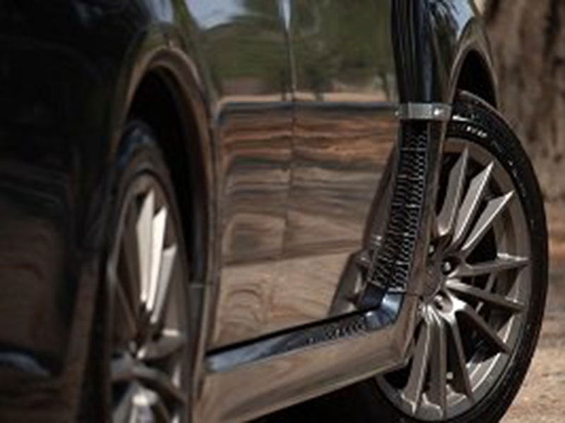 Close-up of a sleek, black car showing shiny alloy wheels and reflective metallic paint