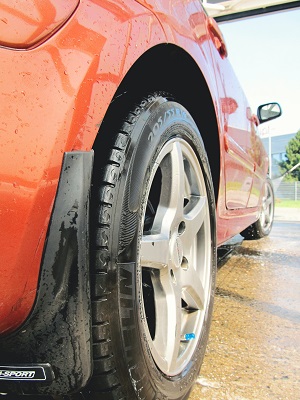 Close-up of a wet red car with shiny silver alloy wheels