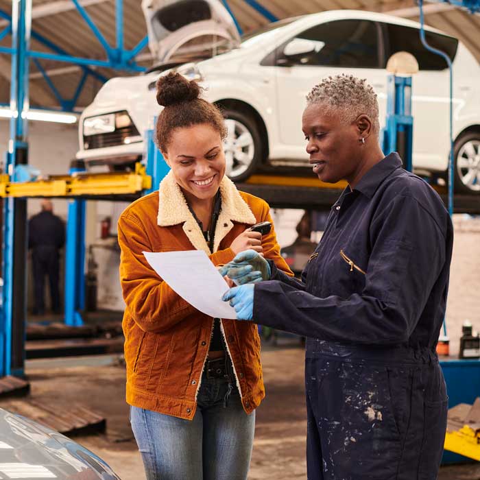 mechanic talking to customer in front of car on lift
