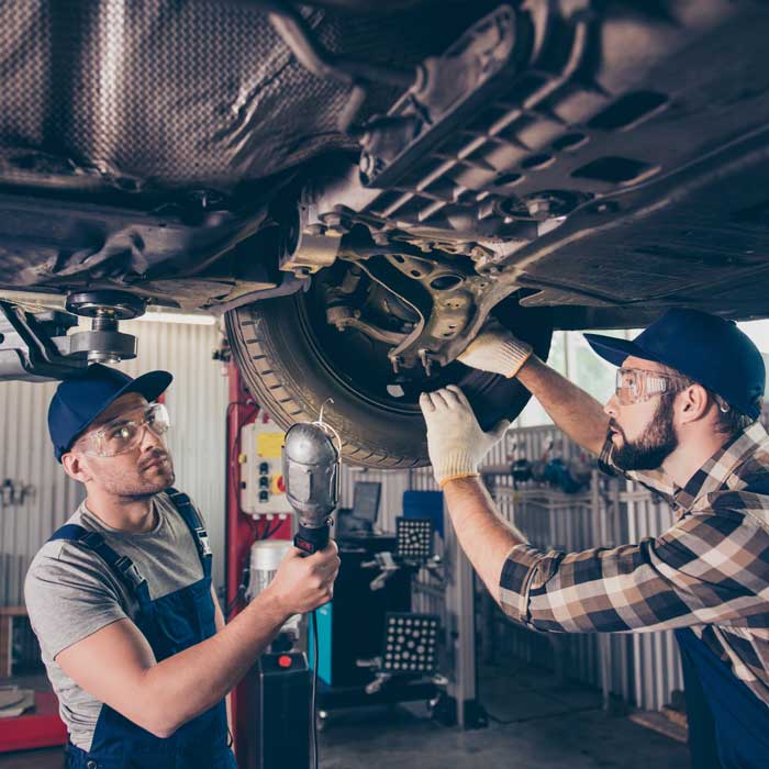 two mechanics looking at car's underbody